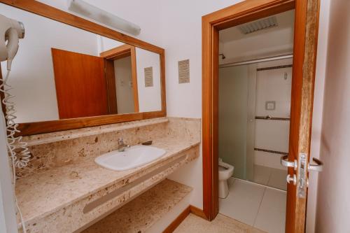 a bathroom with a sink and a mirror and a toilet at Partner Itapoa by Marina in Itapoa