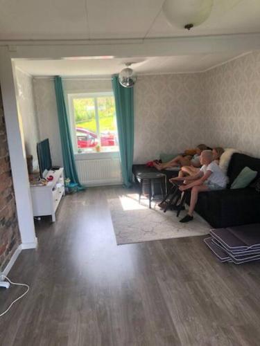 Dos personas sentadas en un sofá en una sala de estar en Huset i skogen med utsikten en Vallsta