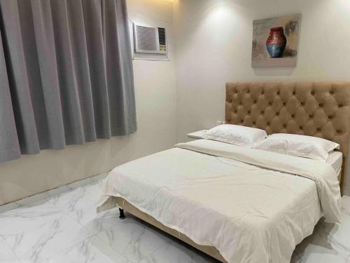 a bedroom with a large bed with white sheets at شقة عصرية واسعة بغرفتي نوم موقع مميز وسط المدينة in Riyadh