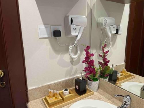 uma casa de banho com lavatório, secador de cabelo e espelho em شقة عصرية واسعة بغرفتي نوم موقع مميز وسط المدينة em Riyadh