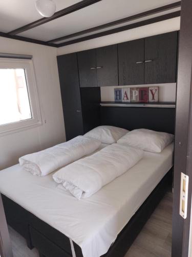 a bed with white pillows on it in a room at Vakantie Chalet Makkum in Makkum
