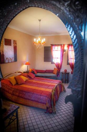 a bedroom with a large bed and a chandelier at Chambre Agdz, Riad 2 Couple only au village naturiste in Cap d'Agde