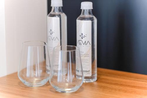 three empty wine glasses and bottles on a wooden table at Hotel Vema in Visoko