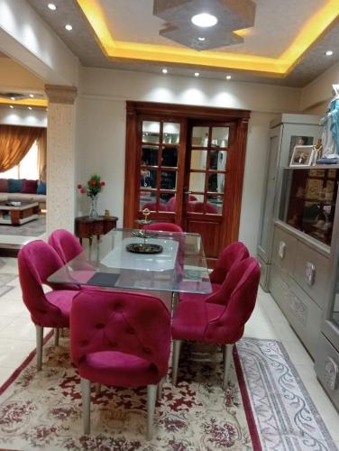 comedor con mesa de cristal y sillas rosas en شبرا مصر, en El Cairo