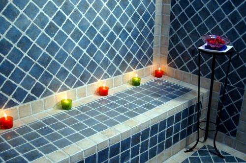 uma casa de banho em azulejos azuis com velas no chão em Suite Bradia, Riad 2 Couple only au village naturiste em Cap d'Agde