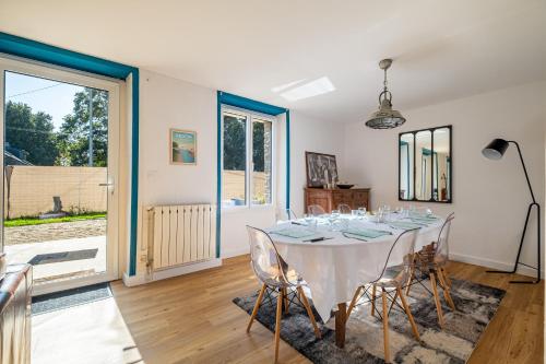 une salle à manger avec une table et des chaises blanches dans l'établissement Le Cottage de Flore - Avec piscine privée chauffée, à Saint-Jean-la-Poterie