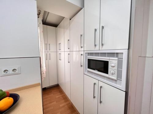 a kitchen with white cabinets and a microwave at Summerlandrota Cordoba8 in Rota