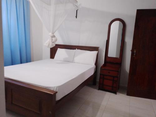 a small bedroom with a bed and a mirror at Sea Side Bay House in Weligama