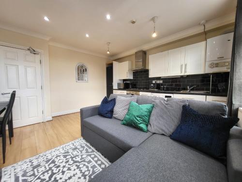 uma sala de estar com um sofá cinzento e uma cozinha em Tooting Bec Central Apartment by London Tube em Londres