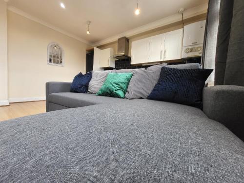 a living room with a gray couch with pillows at Tooting Bec Central Apartment by London Tube in London