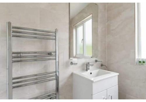 a white bathroom with a sink and a window at Chic 4BR Home in Mitcham Ideal for Families in Mitcham
