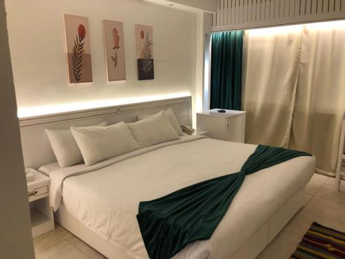 ein Schlafzimmer mit einem großen weißen Bett mit Gemälden an der Wand in der Unterkunft Salma Hotel Cairo in Kairo