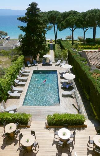 a pool with tables and chairs and a person in a swim at Hôtel La Pinède in Ajaccio