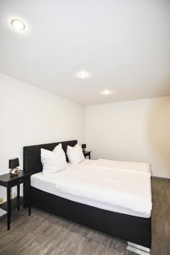 a bedroom with a bed with white sheets and a table at Hotel zur Schlemmerscheune in Weilerbach