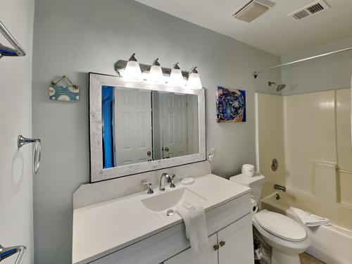 La salle de bains est pourvue d'un lavabo, de toilettes et d'un miroir. dans l'établissement Saltcreek Sunsets, à Tybee Island