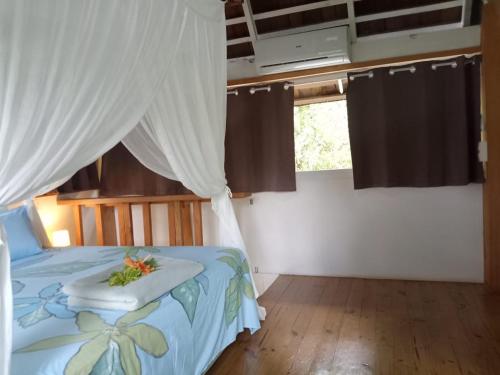 una camera con un letto a baldacchino bianco di Manta Lodge avec 4x4 Pleine nature a Haapu