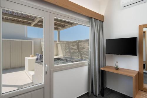 een kamer met een glazen schuifdeur en een tv bij New Sea Serenity Villas Next to the Sea With Private Jacuzzi in Vlychada