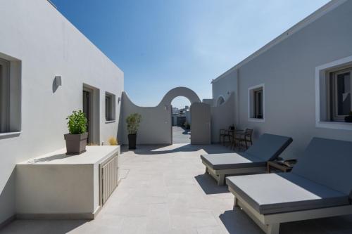 a patio with chairs and tables on a building at New Sea Serenity Villas Next to the Sea With Private Jacuzzi in Vlychada
