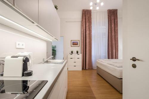a kitchen with a sink and a bed in a room at Klauzál Garden City Apartments- studio K32 in Budapest