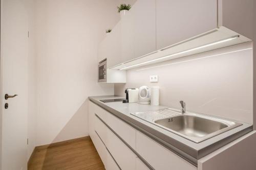 a kitchen with a sink and white cabinets at Klauzál Garden City Apartments- studio K32 in Budapest