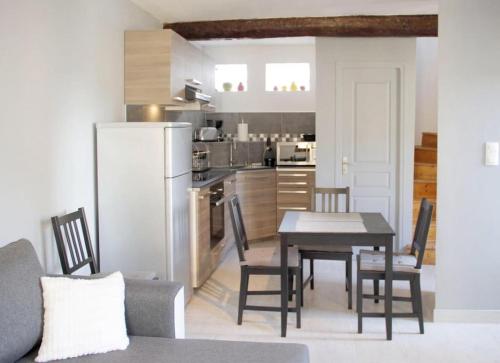 a kitchen and dining room with a table and a refrigerator at Gite les coquelicots ( classé 2* ) Duplex in LʼIsle-sur-la-Sorgue