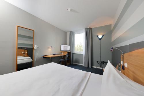 a bedroom with a bed and a desk and a window at Median Hotel Hannover Messe in Hannover