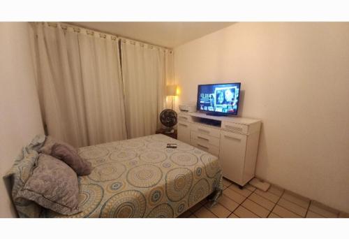 a small bedroom with a bed and a television at Apartamento Barra in Salvador