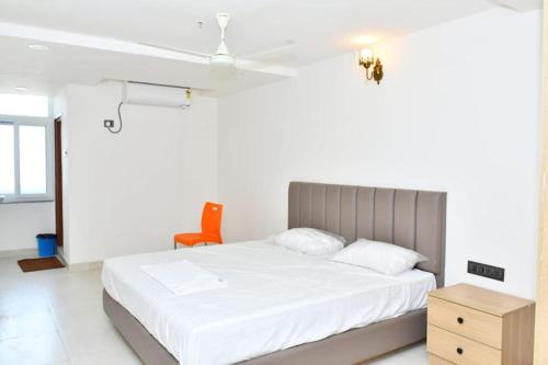 a bedroom with a white bed and a orange chair at SWAGATH RESIDENCY in Devarkonda