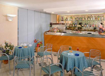 a restaurant with tables and chairs and a bar at Hotel Bella Romagna in Rimini