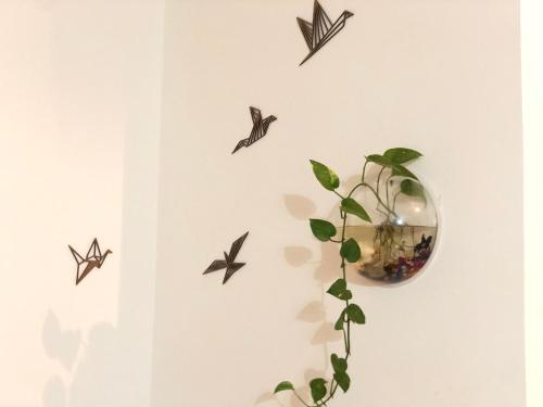 a wall with birds and a plant and a mirror at Sapthagiri Nest in Chikmagalūr
