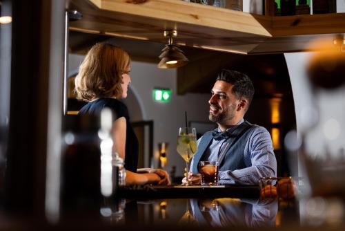 a man and a woman sitting at a bar at Waldhotel Arosa in Arosa