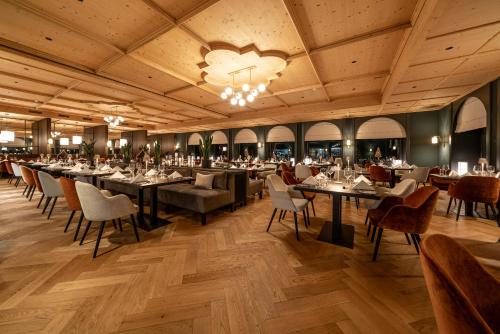 una sala da pranzo con tavoli, sedie e lampadario a braccio di Waldhotel Arosa a Arosa