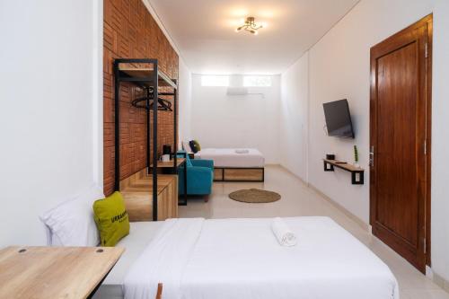 ジョグジャカルタにあるUrbanview Griya Kusumo Seturan Yogyakartaのベッドルーム(白いベッド2台、テレビ付)