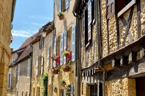 an alley in an old town with buildings and flowers at Dôme géodésique au cœur de la forêt in Montignac