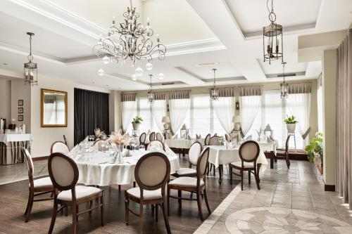 un comedor con mesas y sillas blancas y una lámpara de araña en Hotel Spa Laskowo, en Jankowice