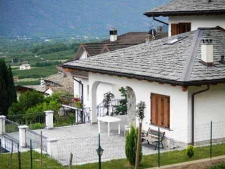 a white house with a bench on a patio at APPARTAMENTI in Villa Isabella in Bianzone
