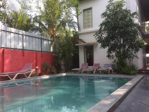 une piscine avec des chaises et une maison dans l'établissement Leena marari beach house, à Alappuzha