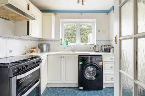 a kitchen with a washing machine and a window at Haven Home in Bristol