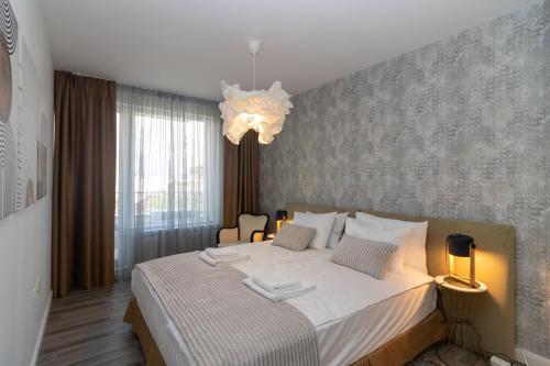 um quarto com uma grande cama branca e um lustre em Contemporary Charm in Old Sofia em Sófia