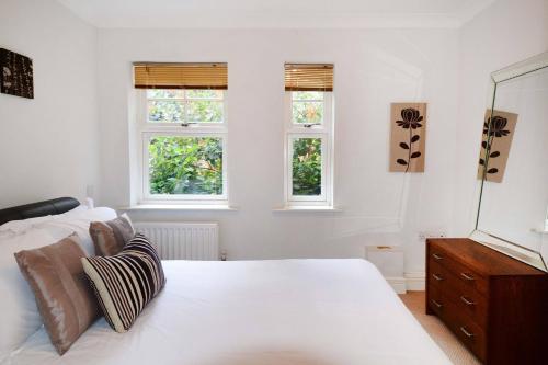 a white bedroom with a bed and two windows at Elizabeth Jennings Way in Oxford
