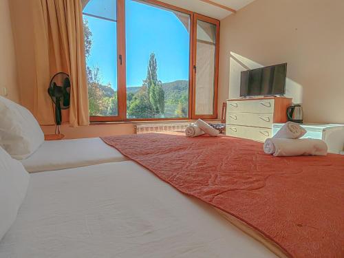 - une chambre avec un grand lit et une grande fenêtre dans l'établissement Къща за гости Сборяна, à Gramatikovo