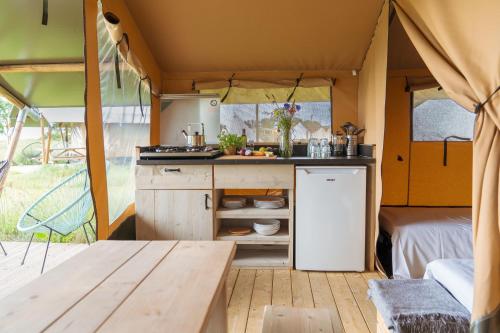 una cocina dentro de una caravana con una mesa y una mesa en Laguna Beach Family Camps Öland, en Mörbylånga