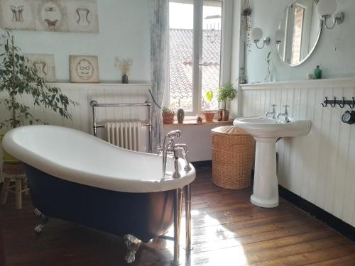 ein Badezimmer mit einer Badewanne und einem Waschbecken in der Unterkunft A l'école... buissonnière in Montmorillon