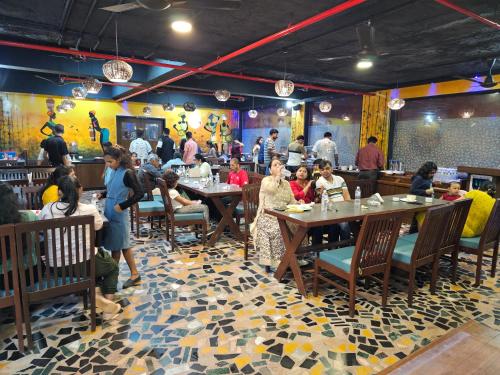 Misty Meadows, Lonavala في لونافالا: مجموعة من الناس يجلسون على الطاولات في المطعم