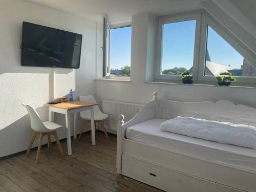 a bedroom with a bed and a table and a tv at Über den Dächern von Essen in Essen