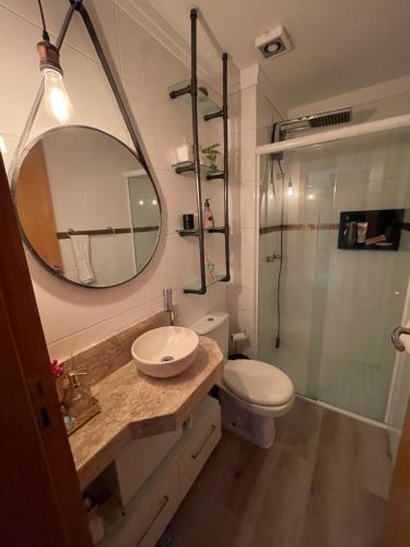 uma casa de banho com um lavatório e um chuveiro com um espelho. em Apto duplex Lagoa do Violão em Torres