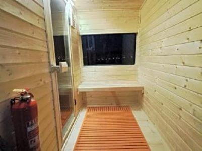 eine kleine Sauna mit einem Fenster und einem Feuerlöscher in der Unterkunft TreeHouses Ljubač Glamping Robinson in Ljubač