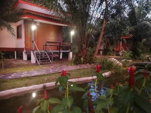 a house with a pond in front of a house at สบายคันทรีรีสอร์ท ปากเมงSa-buy country resort Pak Meng in Sikao
