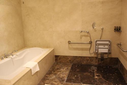 a bathroom with a bath tub and a towel at Grand Regency Doha, Trademark Collection by Wyndham in Doha