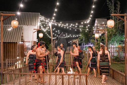 un grupo de personas caminando en una terraza de madera por la noche en Rumhaoy Maison, en Phumĭ Pu Pal